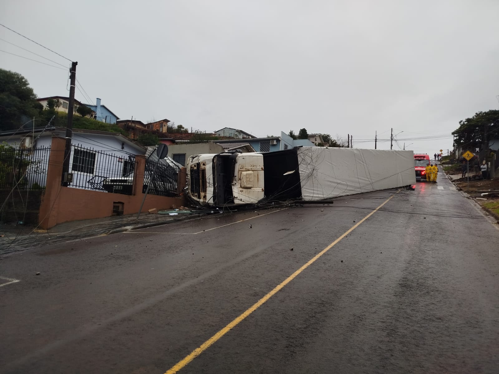 Carreta tomba ao bater em carro e atingir muros de residências