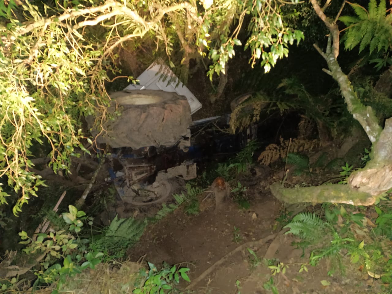 Mulher fica embaixo de trator tombado em barranco de 5 metros