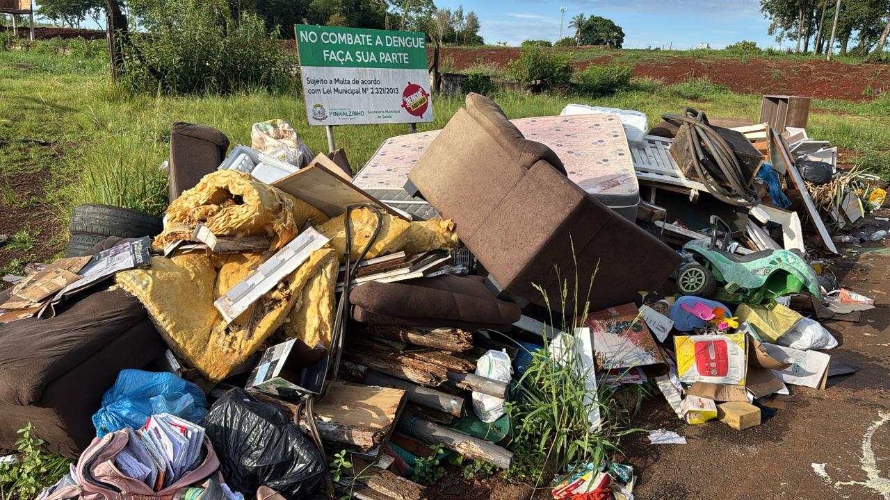 Entulho com água parada é encontrado em frente à placa de alerta contra a dengue