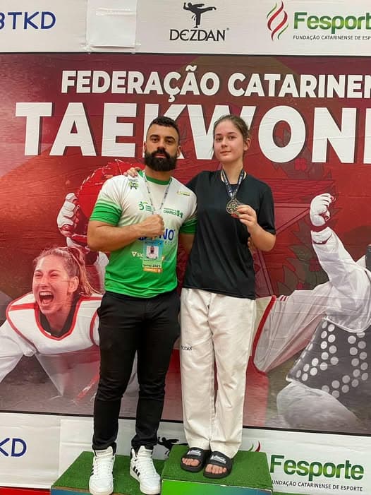 Bianca no lugar mais alto do pódio ao lado de seu treinador (Foto: Divulgação)