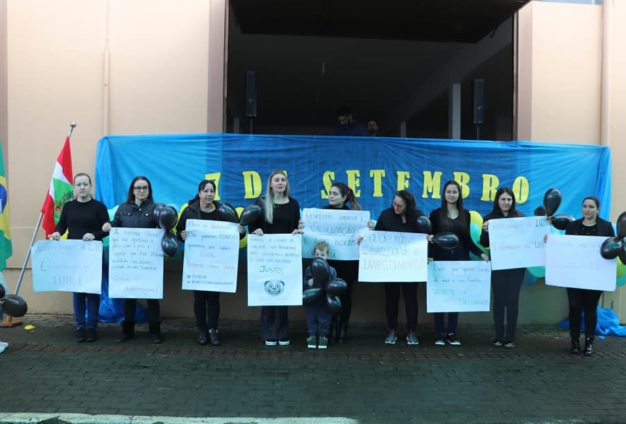 Durante o ato cívico em Nova Erechim, equipe de enfermagem levou cartazes para cobrar suspensão do piso salarial  (Foto: Gilmar Bortese )
