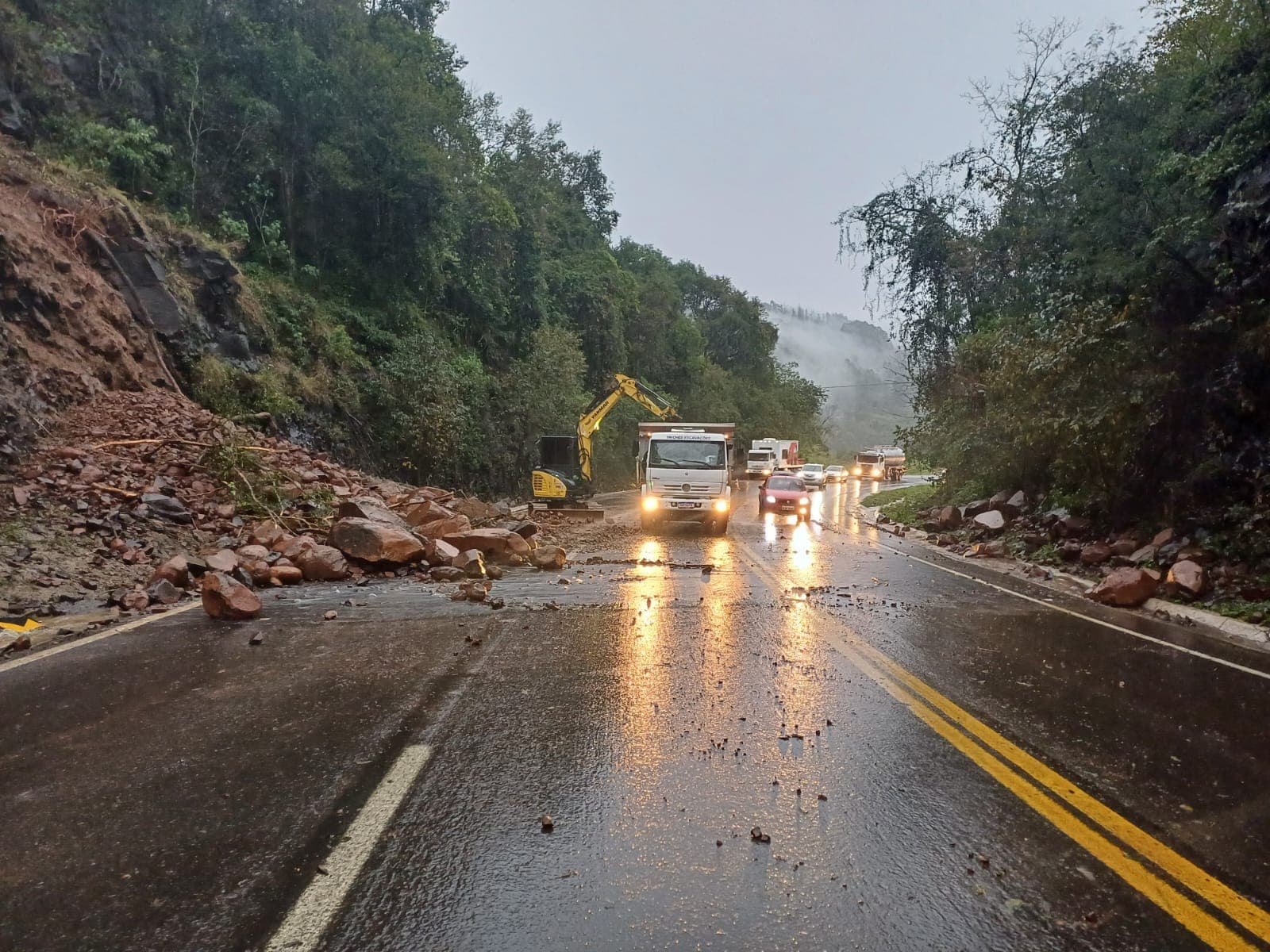 Pedras caem sobre a pista após as chuvas e equipes realizam a limpeza da rodovia, enquanto o tráfego permanece em meia pista com controle da PRF. (Foto por Divulgação)