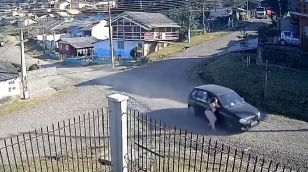 Mulher ficou agarrada na porta de veículo (Foto: Câmera de segurança)