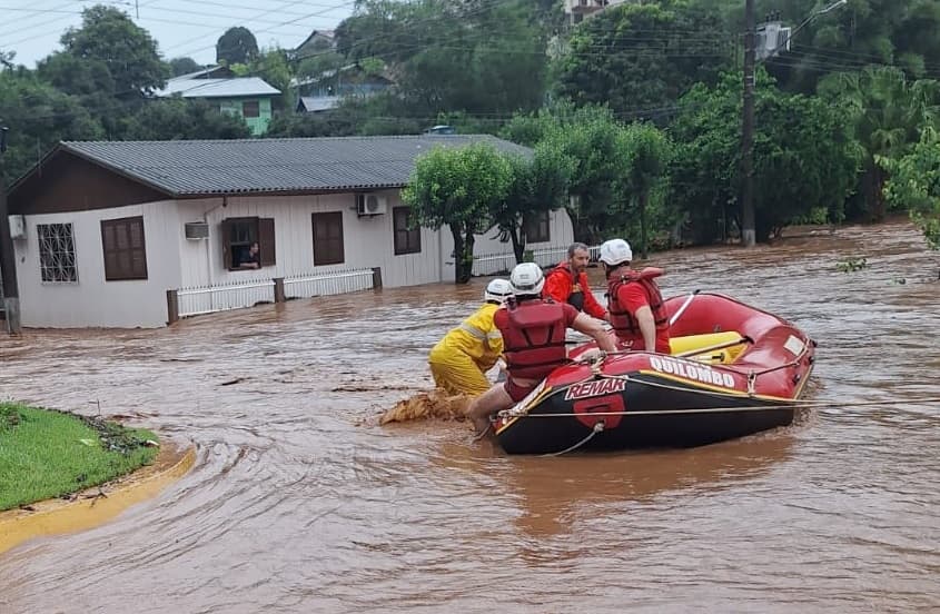 Bombeiros usam bote para resgatar moradores (Foto: Divulgação)
